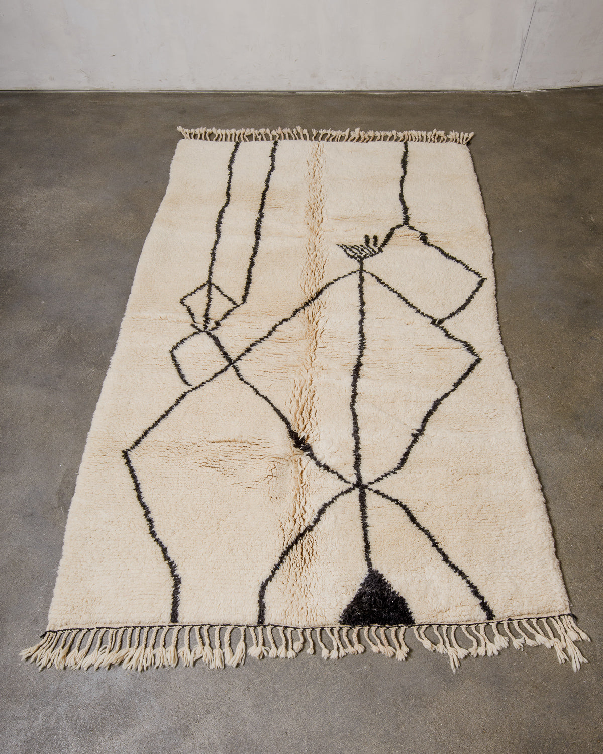 Beige and black minimalist patterned rug on a concrete floor
